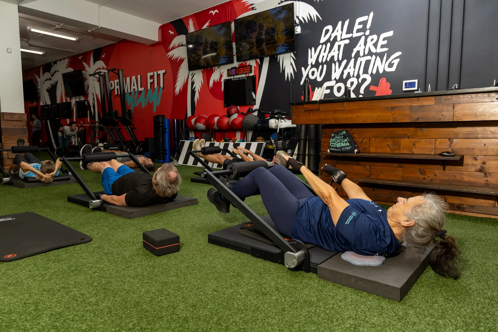 Adults over 50 perform coached ISOPHIT isometric strength exercises on the floor at Primal Fit Miami.